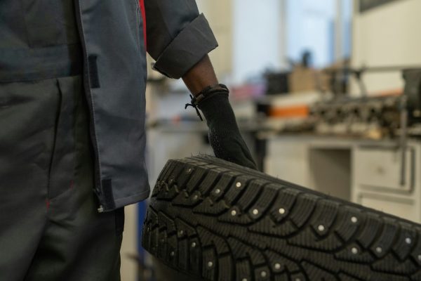 mechanic-holding-tire-in-workshop-F5WQBBP